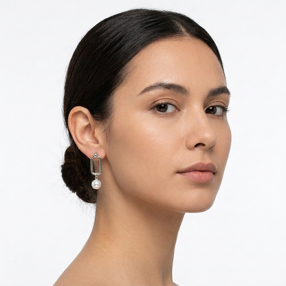Modelka z geometrycznym kolczykiem w srebrnym kolorze ze sztuczną perłą na białym tle