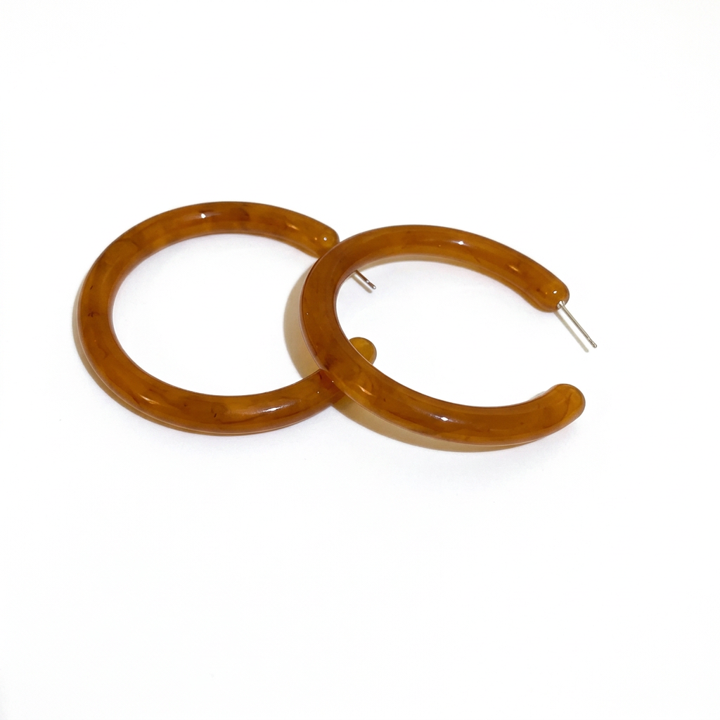 Para brązowych kolczyków z żywicy w kształcie otwartych kółek na białym tle